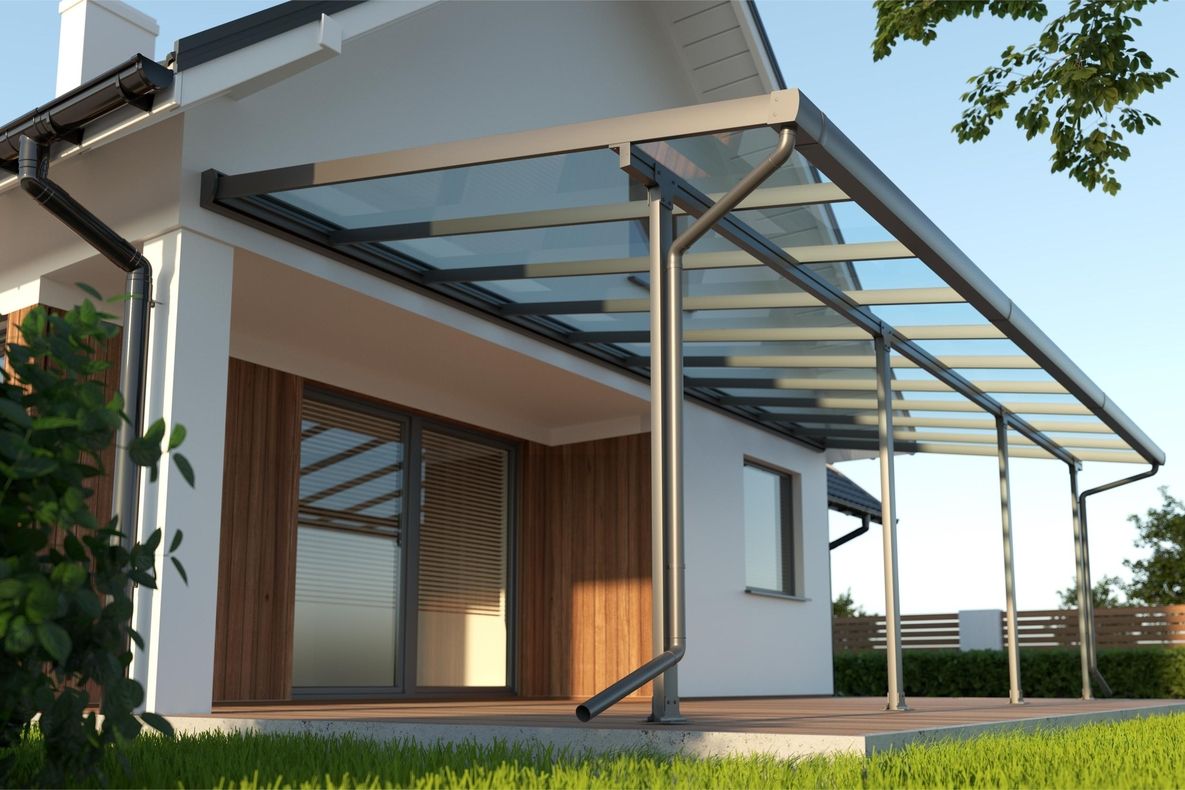 Moderne Terrasse mit Glasdach und weißen Stützpfeilern an einem weißen Haus mit Holzverkleidung